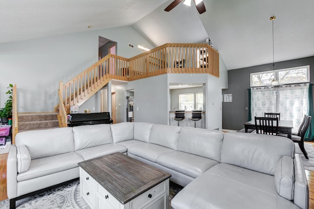 living area featuring visible vents, a ceiling fan, wood finished floors, stairs, and high vaulted ceiling