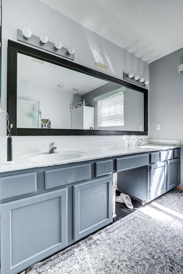 full bathroom featuring a sink, a textured ceiling, and double vanity