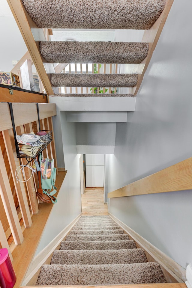 stairway with wood finished floors and baseboards