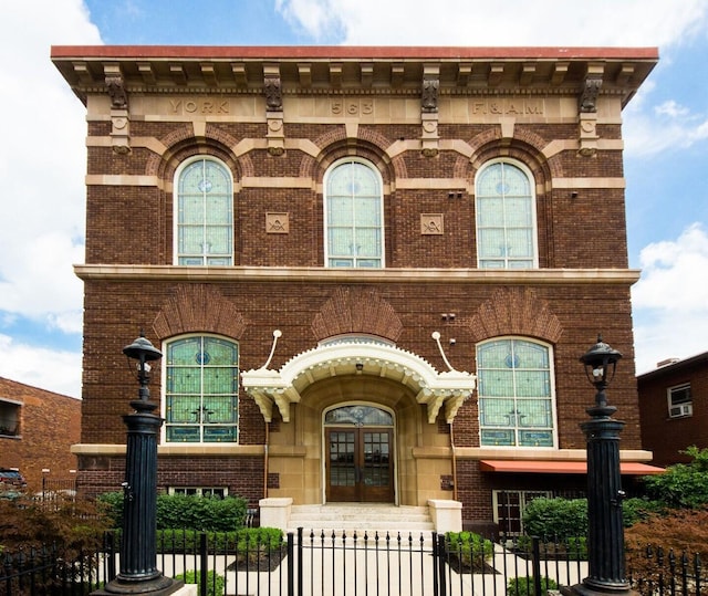 view of front of house with a fenced front yard, brick siding, and french doors