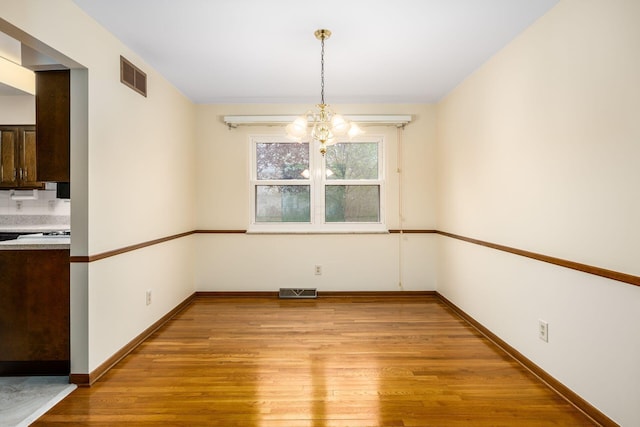 unfurnished dining area featuring a chandelier, light wood-type flooring, and visible vents