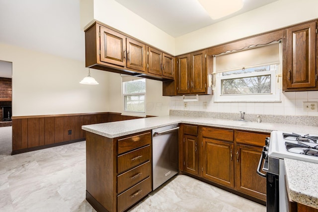 kitchen with a sink, gas range oven, light countertops, dishwasher, and a peninsula