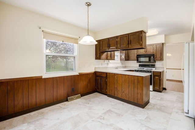kitchen with visible vents, light countertops, a wainscoted wall, white appliances, and a peninsula