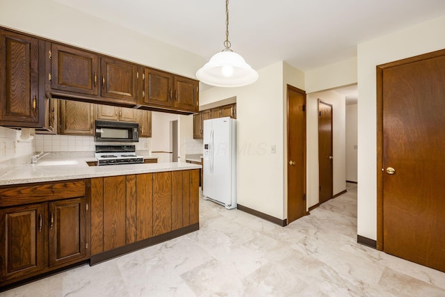 kitchen with decorative backsplash, white appliances, light countertops, and a sink