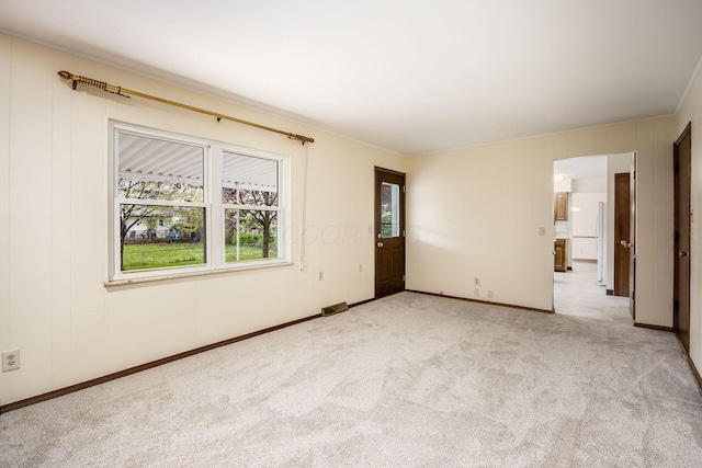 spare room featuring light colored carpet and baseboards