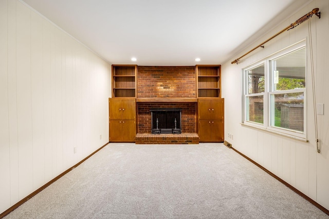 unfurnished living room with baseboards, built in shelves, carpet, and a fireplace