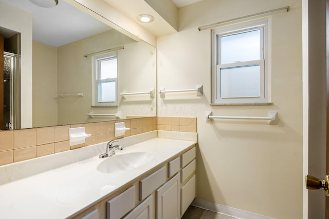 bathroom featuring vanity, baseboards, and backsplash