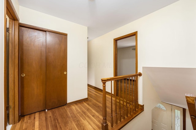 hall with an upstairs landing, wood finished floors, and baseboards