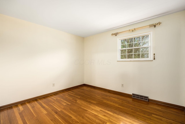 unfurnished room with baseboards, visible vents, and wood finished floors