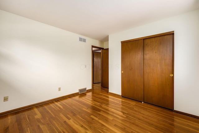 unfurnished bedroom featuring visible vents, wood finished floors, and baseboards