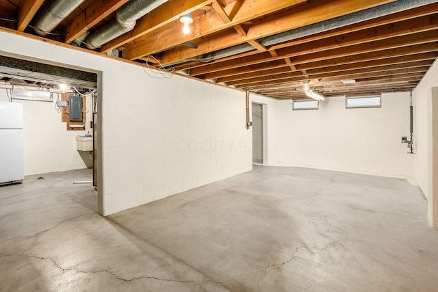 basement featuring electric panel and freestanding refrigerator