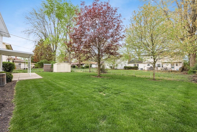 view of yard with an outbuilding, fence, a storage unit, and a patio area