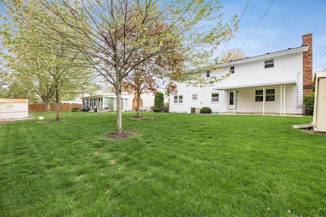 rear view of house featuring a lawn, fence, a chimney, and a patio