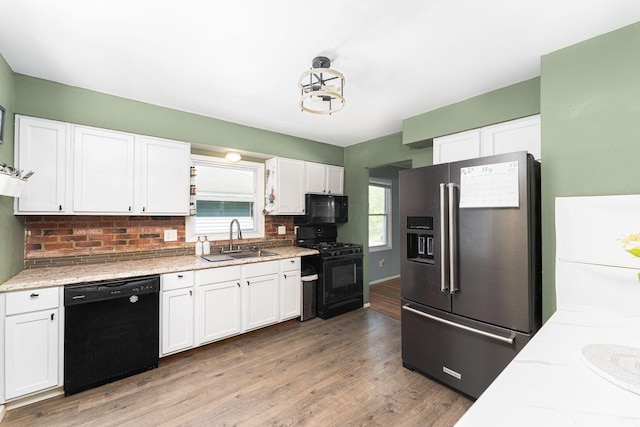 1898 Fenton St, Columbus, OH 43224 - kitchen featuring black appliances, a sink, white cabinetry, decorative backsplash, and light wood-type flooring