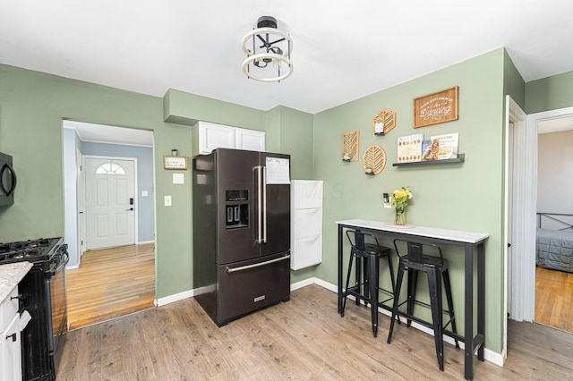 1898 Fenton St, Columbus, OH 43224 - kitchen with black appliances, white cabinetry, light wood-type flooring, and light countertops