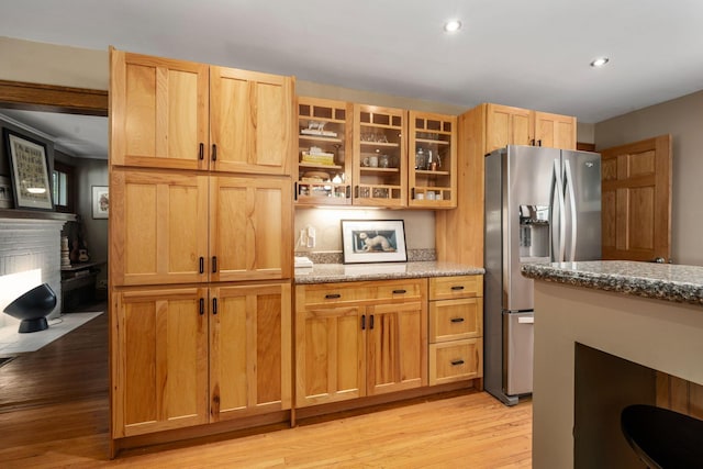 1397 Glenn Ave, Columbus, OH 43212 - kitchen featuring stainless steel refrigerator with ice dispenser, light wood-type flooring, light stone counters, a brick fireplace, and glass insert cabinets