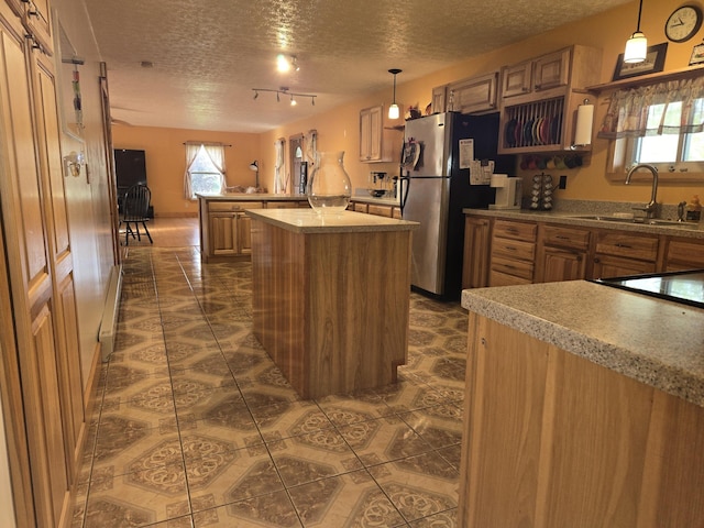 kitchen with a sink, a textured ceiling, a peninsula, and dark tile patterned flooring