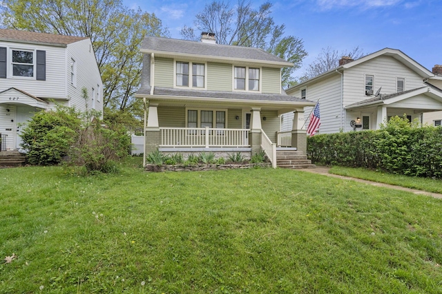 view of front of house featuring a front lawn, covered porch, and a chimney