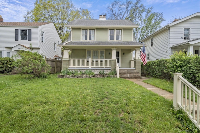 view of front facade featuring a porch, fence, a chimney, and a front yard
