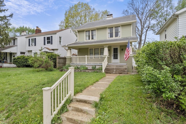 view of front facade with a front yard, covered porch, and a chimney