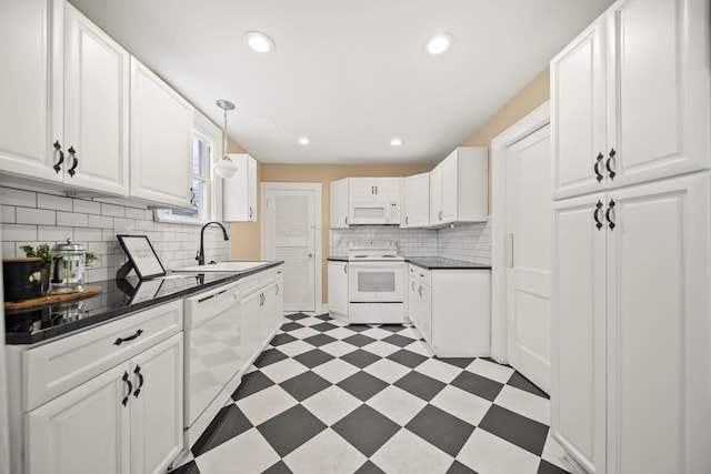 kitchen with dark countertops, white appliances, light floors, white cabinetry, and a sink