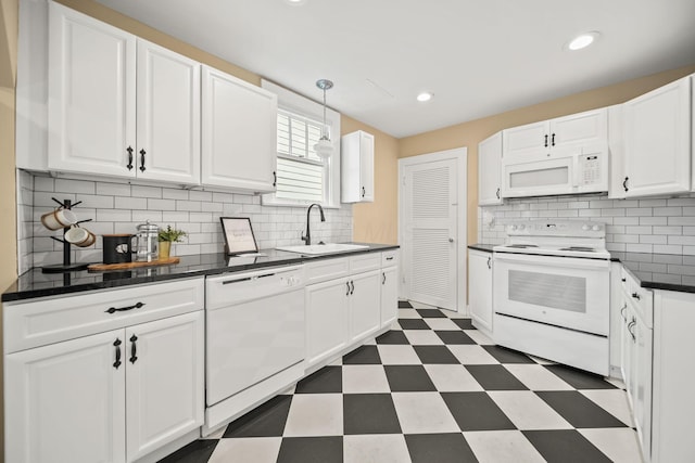 kitchen with dark countertops, white appliances, white cabinets, dark floors, and a sink