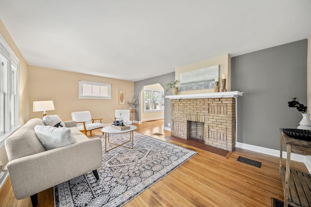 living room with arched walkways, baseboards, wood finished floors, and visible vents