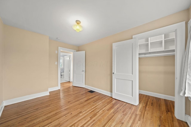 unfurnished bedroom featuring a closet, baseboards, visible vents, and light wood-type flooring