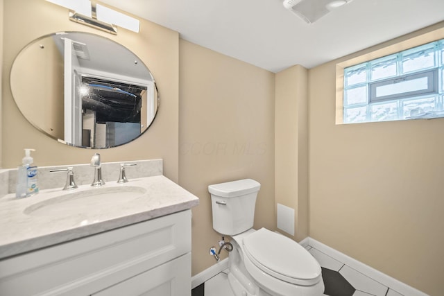 half bathroom with baseboards, vanity, and toilet