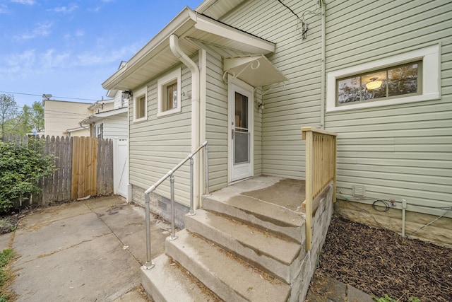 view of exterior entry with a patio and fence