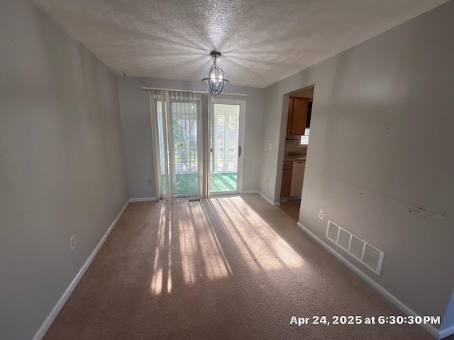 unfurnished dining area with baseboards, a chandelier, a textured ceiling, and visible vents