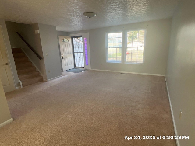 interior space with carpet, a textured ceiling, baseboards, and stairs