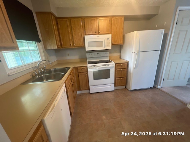 kitchen featuring a sink, brown cabinetry, light tile patterned flooring, white appliances, and light countertops