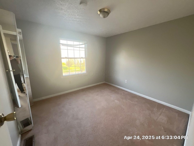 empty room featuring baseboards, carpet flooring, and visible vents