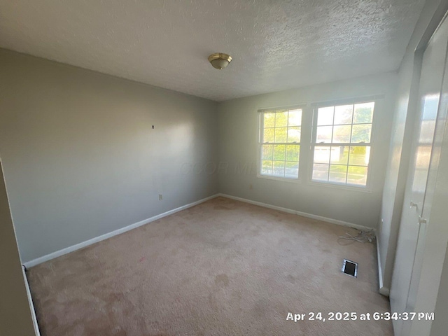 unfurnished room with baseboards, carpet flooring, a textured ceiling, and visible vents