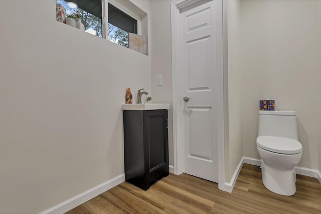 bathroom with baseboards, a sink, wood finished floors, and toilet