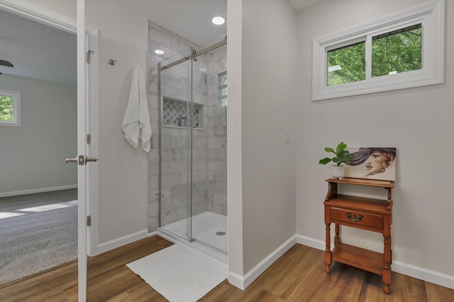 bathroom featuring wood finished floors, baseboards, and a stall shower