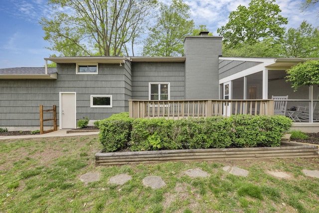 rear view of property with a chimney, a sunroom, and a deck