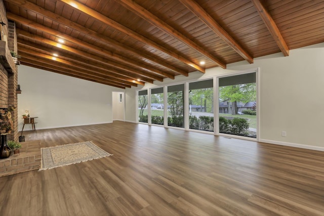 unfurnished living room with baseboards, plenty of natural light, vaulted ceiling with beams, and wood finished floors