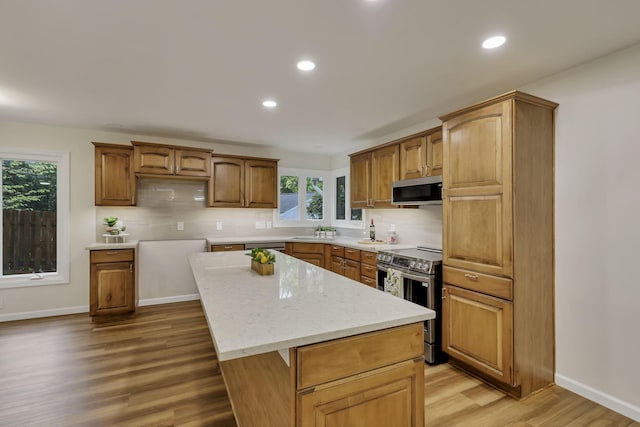 kitchen with stainless steel appliances, recessed lighting, decorative backsplash, light wood-type flooring, and a kitchen island