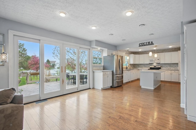 kitchen with white cabinetry, stainless steel appliances, a textured ceiling, and wood finished floors