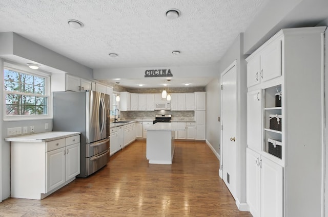 kitchen with white cabinets, stainless steel appliances, a wealth of natural light, and wood finished floors