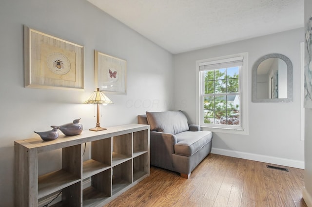 living area featuring wood finished floors, visible vents, and baseboards