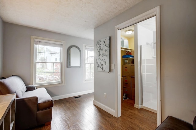 living area featuring dark wood finished floors, visible vents, a textured ceiling, and baseboards