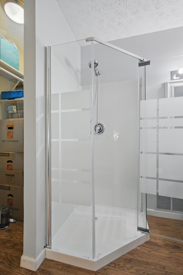 bathroom featuring a stall shower, a textured ceiling, and wood finished floors