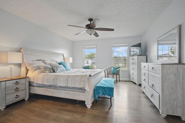 bedroom with dark wood-type flooring, a ceiling fan, baseboards, and a textured ceiling