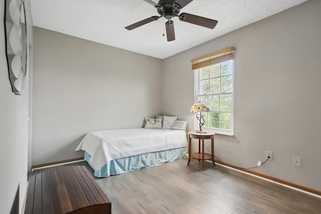 bedroom with a ceiling fan, wood finished floors, and baseboards