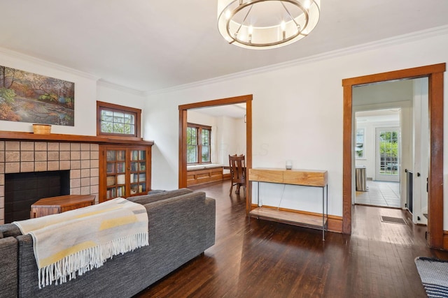 living area with wood finished floors, crown molding, a fireplace, baseboards, and a chandelier