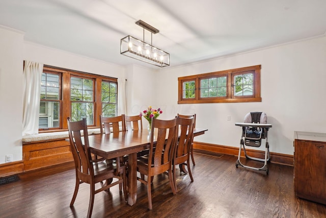 dining area featuring dark wood finished floors, baseboards, and crown molding