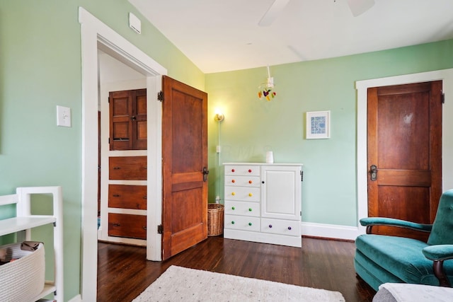 living area featuring dark wood-style flooring, ceiling fan, and baseboards